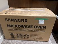 Sealed cardboard box labeled Samsung Microwave Oven with handling symbols