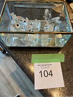 Five Swarovski crystal animal figurines displayed in a glass box with mirrored sides.
