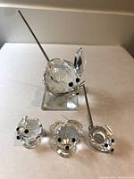 Front view photo of 4 Swarovski crystal mice in various poses on white surface.