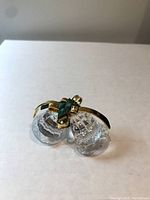 Two clear faceted crystal bells with gold-tone accents and green detailing, photographed on a white background.