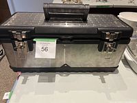 Closed metal toolbox with black plastic top and two metal latches, showing exterior condition.