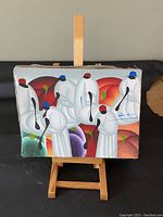 Front view of one small canvas painting showing abstract floral modern design in white, red, purple, green colors, displayed on wooden easel