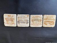 Four square stoneware coasters with brownish vintage Chateau wine estate illustrations shown from the cork bottom side.