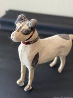 Side profile of antique terrier dog toy showing wool texture, black patches, leather collar with metal studs.