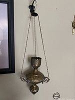 Church censer hanging against wall, showing overall design with hanging chains and decorative handles.