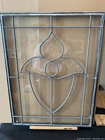 Photo of single antique leaded glass window showing acorn-shaped lead design and clear glass panes with metal frame