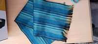 Full view of scarf folded showing blue shades and fringed end