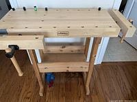 Front view showing solid oak benchtop, dog holes, face vice and lower storage shelf