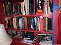 Three shelves of books and CDs including a variety of reference, travel, art, literature books and classical music CDs in cases and box sets.