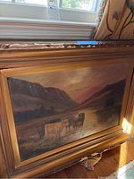 Frontal view of the framed painting showing the full scene of oxen in valley stream with window light reflection on canvas.