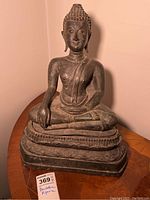 Front view of seated Buddha statue on table showing overall shape and proportions
