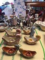 Full lot showing lady and gentleman figurine candle holders, five boat-shaped candle holders, and seahorse figurine arranged on a table.