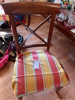 Chair showing wooden X-back and silk striped seat slipcover with red, yellow, cream colors