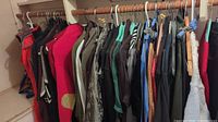 Photo of ladies clothing hung on rod showing sweaters, jackets and outerwear mostly in dark, red and white tones.