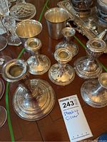 Group view of six weighted sterling silver candlesticks on wooden surface