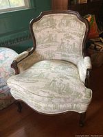 Front angle view of a vintage Bergère armchair with worn toile fabric upholstery and dark wood frame.