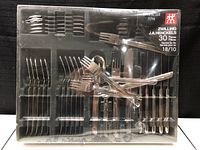 Top view of the 30 piece flatware set in original packaging showing forks, knives, and spoons, labeled as Manhattan model service for six, 18/10 stainless steel.