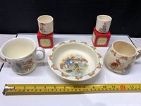 Five Royal Doulton Bunnykins ceramic pieces arranged with measuring tape indicating size.