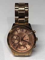 Front view of the Guess U107L3 gold tone chronograph watch showing the dial, hands, subdials, and bracelet.