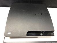 Top view of black PS3 Slim console showing matte finish and PS3 logo.
