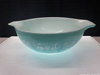Side view of large turquoise blue Pyrex mixing bowl showing white tropical hula dancer artwork.
