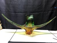 Front view of chalet style glass centerpiece showing extended green and amber wings with yellow center