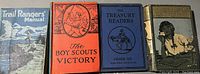 Four vintage books arranged side by side: Trail Ranger's Manual with a mountainous cover, The Boy Scout's Victory with an orange cover featuring a scout emblem, The Treasury Readers Grade Six with a blue cover and horse rider illustration, The Laddie with a greenish cover and an illustrated black dog.