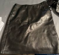 Front view of a smooth black leather skirt showing texture and cut.
