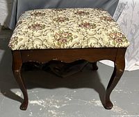 Photo showing Bombay bench with detailed carved wooden legs and floral upholstered top.