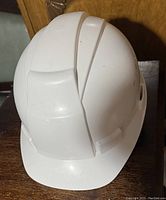 Side view of white construction hard hat showing outer shell and front brim