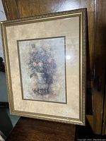 Full view of the framed floral arrangement print showing the artwork, matting, and decorative golden frame