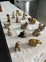Photo of multiple small Wade figurines arranged on a white cloth, showing animals and human figures with detailed painting and glossy finish.