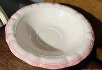 Close-up photo of the large ceramic basin showing white interior with pink rim and scalloped edge.