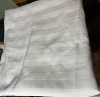 Folded white linen tablecloth with alternating horizontal stripes visible.