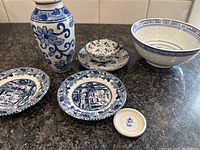 Porcelain vase, large bowl, three small plates, and a small round dish shown on a countertop.