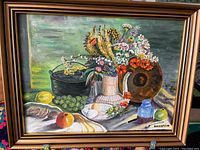 Full image of the original oil still life painting in a wooden frame, showing flowers, fruits, and various objects on a cloth.