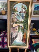 Full view of the vintage painting illustrating a street under an archway with palm trees and buildings.