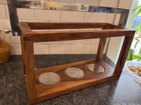 Front and side view of walnut wooden display stand with chrome handle and circular chrome insets.