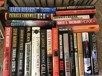Top view of various fiction books by different authors tightly stacked, showing titles and spines for identification.