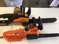 Top view showing the WORX electric chainsaw and BLACK+DECKER electric chainsaw side by side on a table