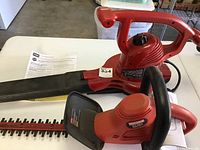 Photo showing the Craftsman hedge trimmer and Toro blower placed on a table along with documentation.