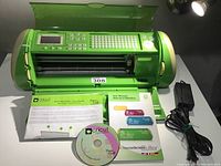 Photo of Cricut Expression machine open, showing keypad, LCD, and cutting area with accessories underneath.