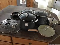 Wide view of all pots, lids and pans on counter showing variety and condition of items