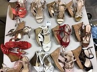 Top view of the large assortment of ladies cork wedge sandals in various colors and brands on white surface.