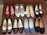 All ten pairs of ladies flat shoes arranged in two rows on a wooden surface showing various styles and colors.