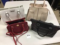 Four handbags displayed on table including white, beige, black, and red options.