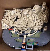Partially assembled Colosseum model and loose bricks on baseplate inside box