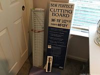 Photo of the Sew Perfect cutting board box showing a 36x72 inch cutting area, folded to 40x12x1 inches, placed near a window and door.