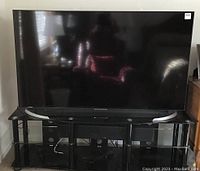 70" TV on black glass stand with soundbar beneath