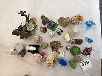 Top-down photo of 26 assorted small ceramic animal figurines, showing variety of species, colors and styles.